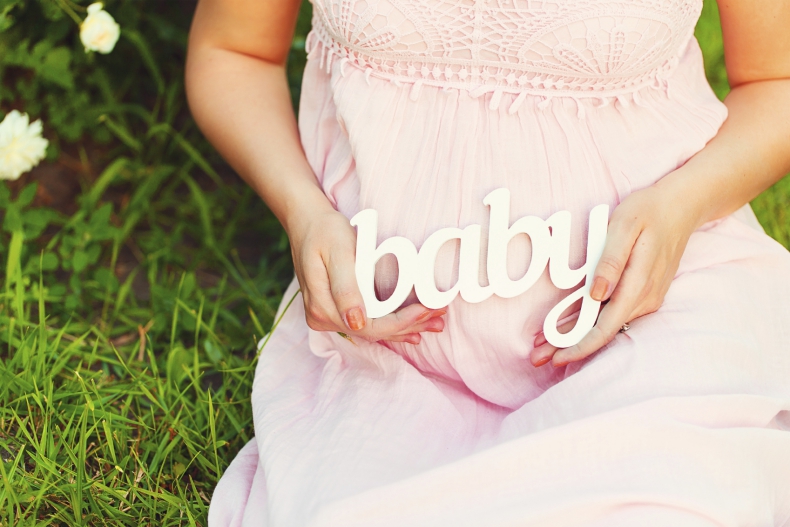 Label "Baby" in the hands of a pregnant woman outdoors