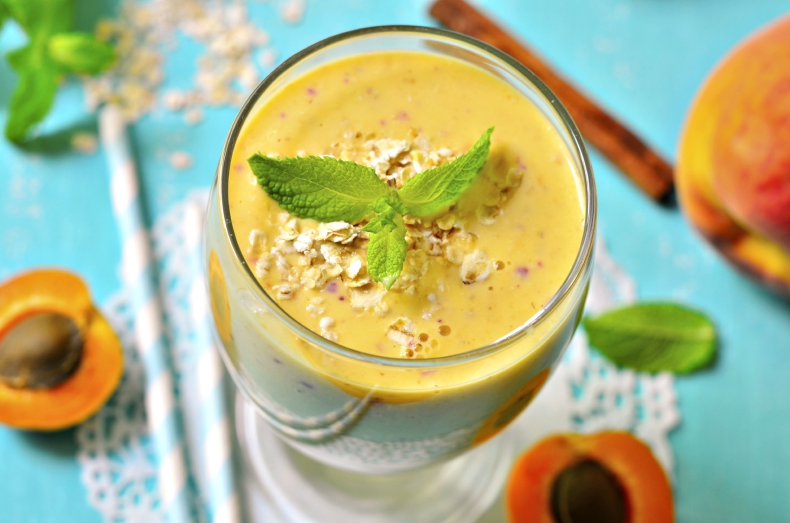 Peach and apricot smoothie in z glass on blue wooden table.
