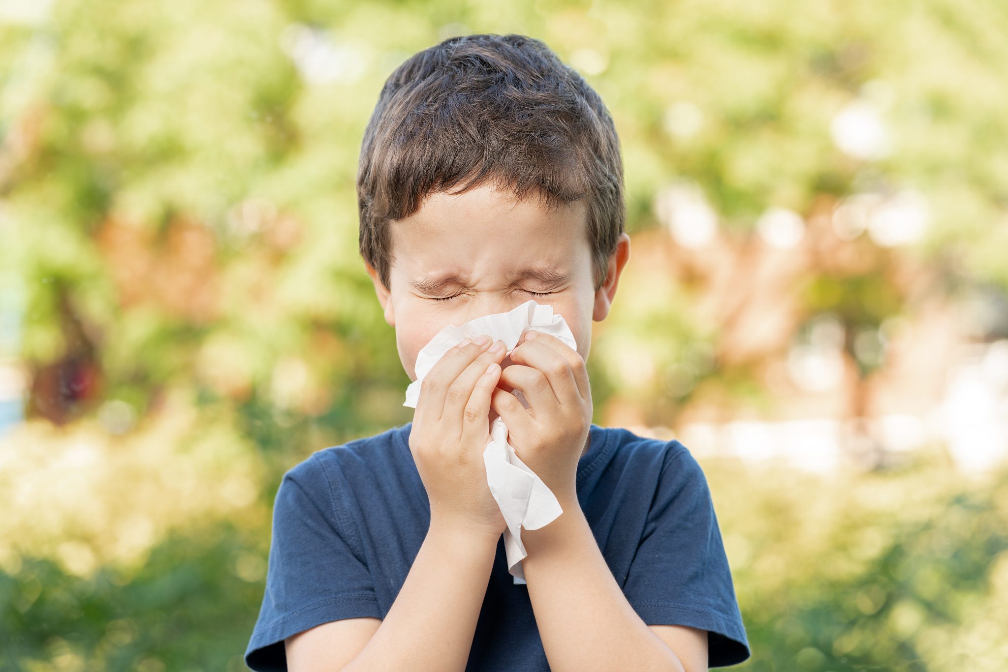 Child sneezing into a tissue